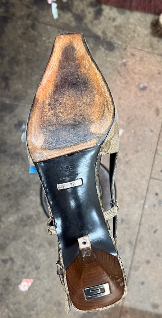 Sole of a worn high-heeled shoe showing scuffed leather and exposed heel tip.