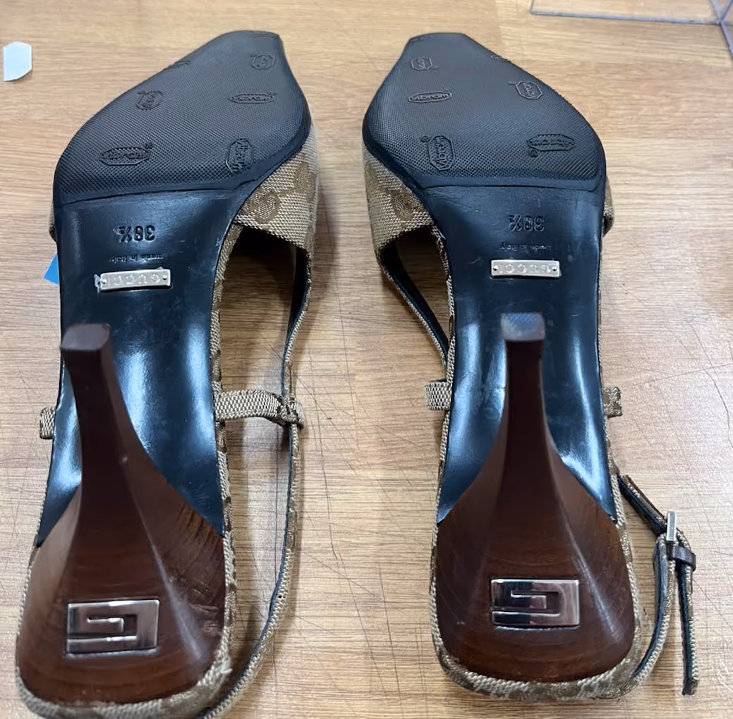 Pair of high-heeled shoes viewed from the sole showing brown heels and textured black soles.