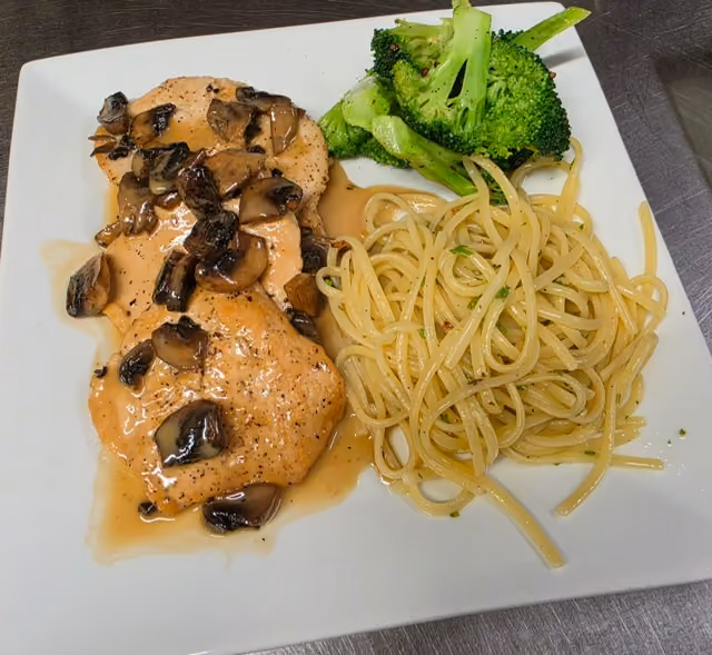 Plate with chicken breast in mushroom sauce, steamed broccoli, and spaghetti pasta with herbs.