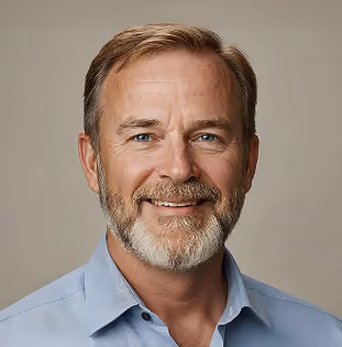 Smiling middle-aged man with light brown hair and beard wearing a light blue collared shirt.