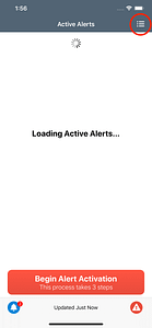 Mobile app screen with a loading spinner under the title 'Active Alerts' and the message 'Loading Active Alerts…', showing a grid menu icon in the top right corner and a red button labeled 'Begin Alert Activation' at the bottom.