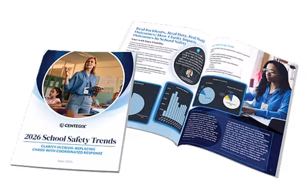 A printed report titled '2026 School Safety Trends' by Centegix with the subtitle 'Clarity in Crisis: Replacing Chaos with Coordinated Response' and the cover image of a woman holding a tablet in a classroom. The report is open showing pages with charts, graphs, and text alongside an image of a woman working on a laptop.