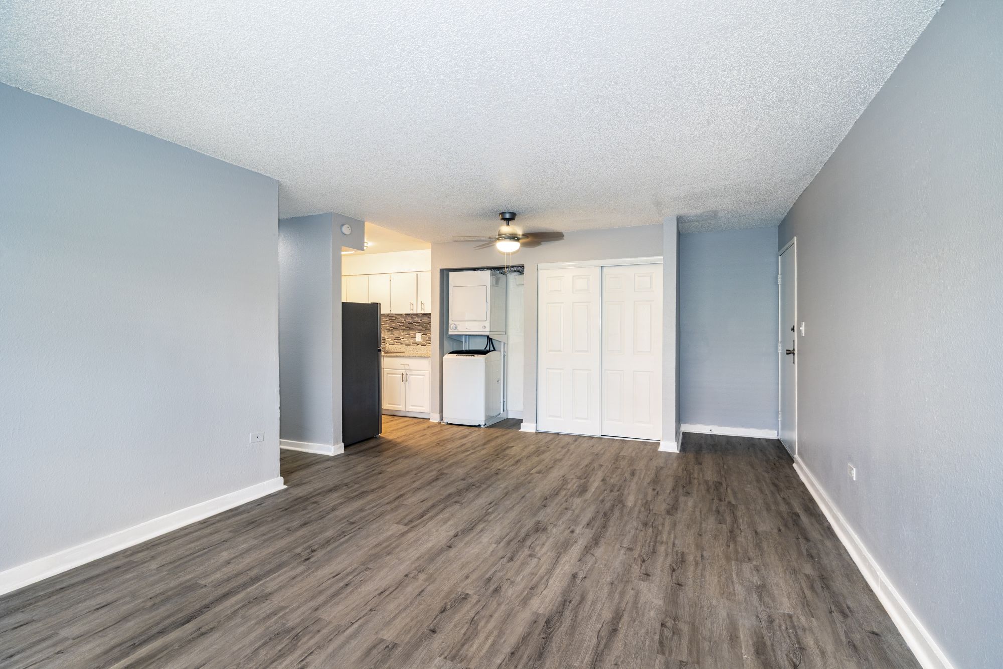 Living room with wood-look flooring and view of coat closet, and washer and dryer