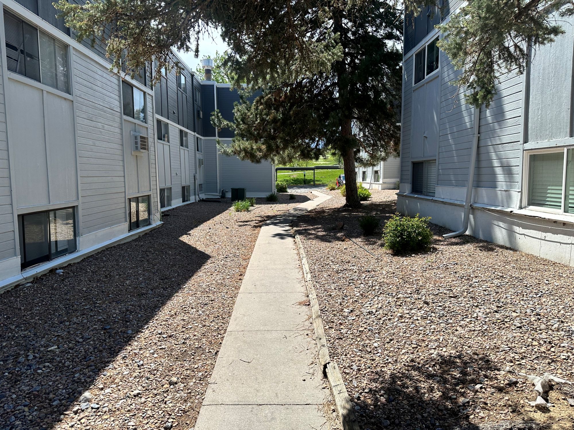 Exterior sidewalk between apartment buildings and grass leading to parking area