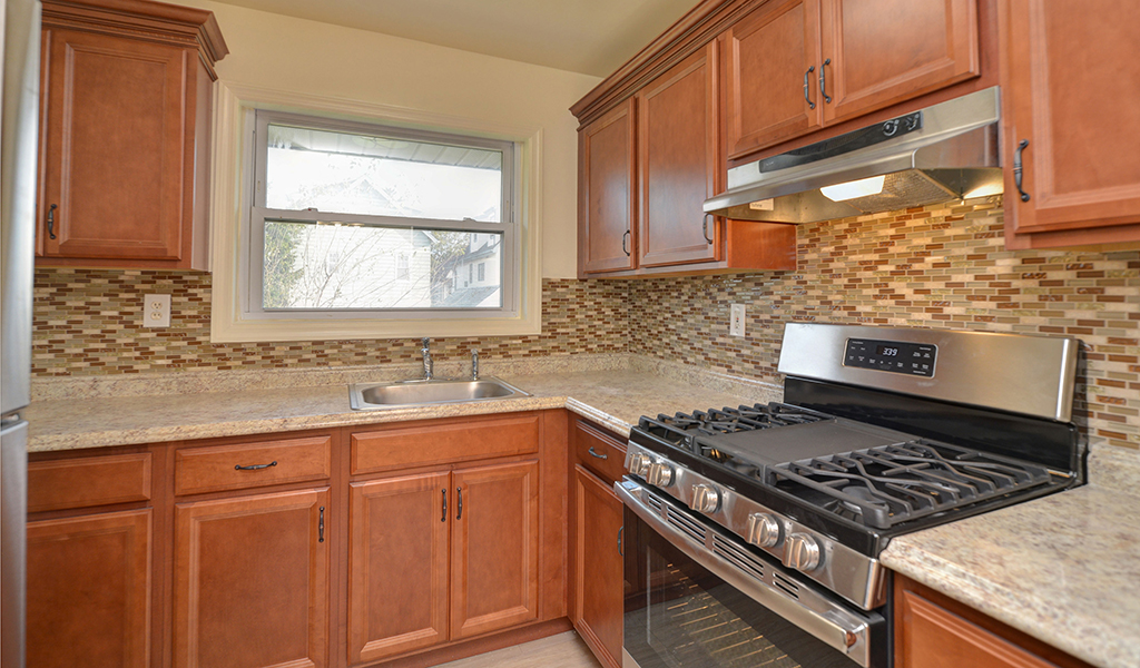View of custom kitchen featuring marble countertops and tiled backsplash