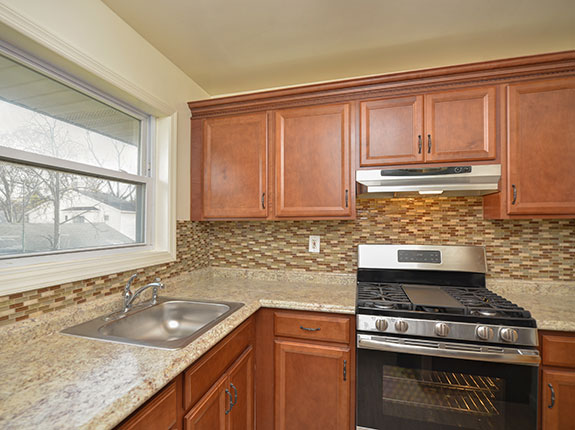 View of custom kitchen featuring marble countertops and tiled backsplash