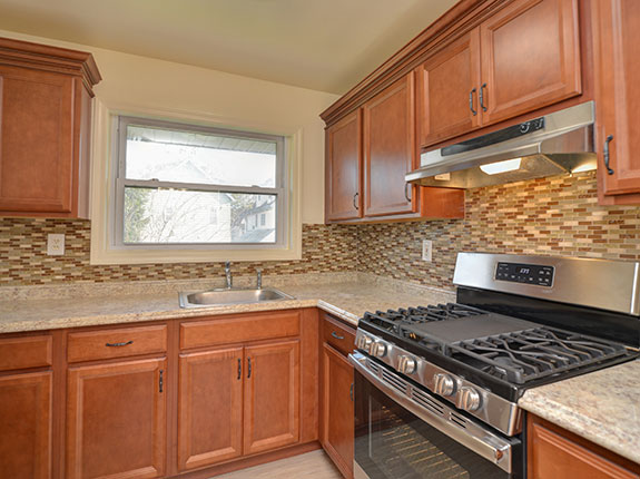 View of custom kitchen featuring marble countertops and tiled backsplash