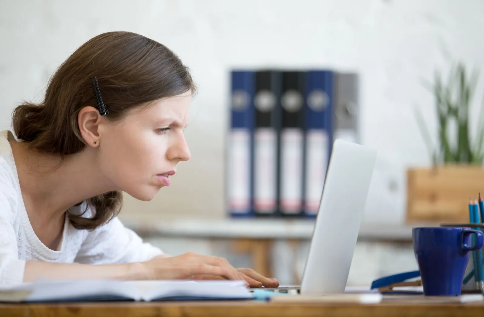 Woman leaning close to her laptop screen, struggling to read