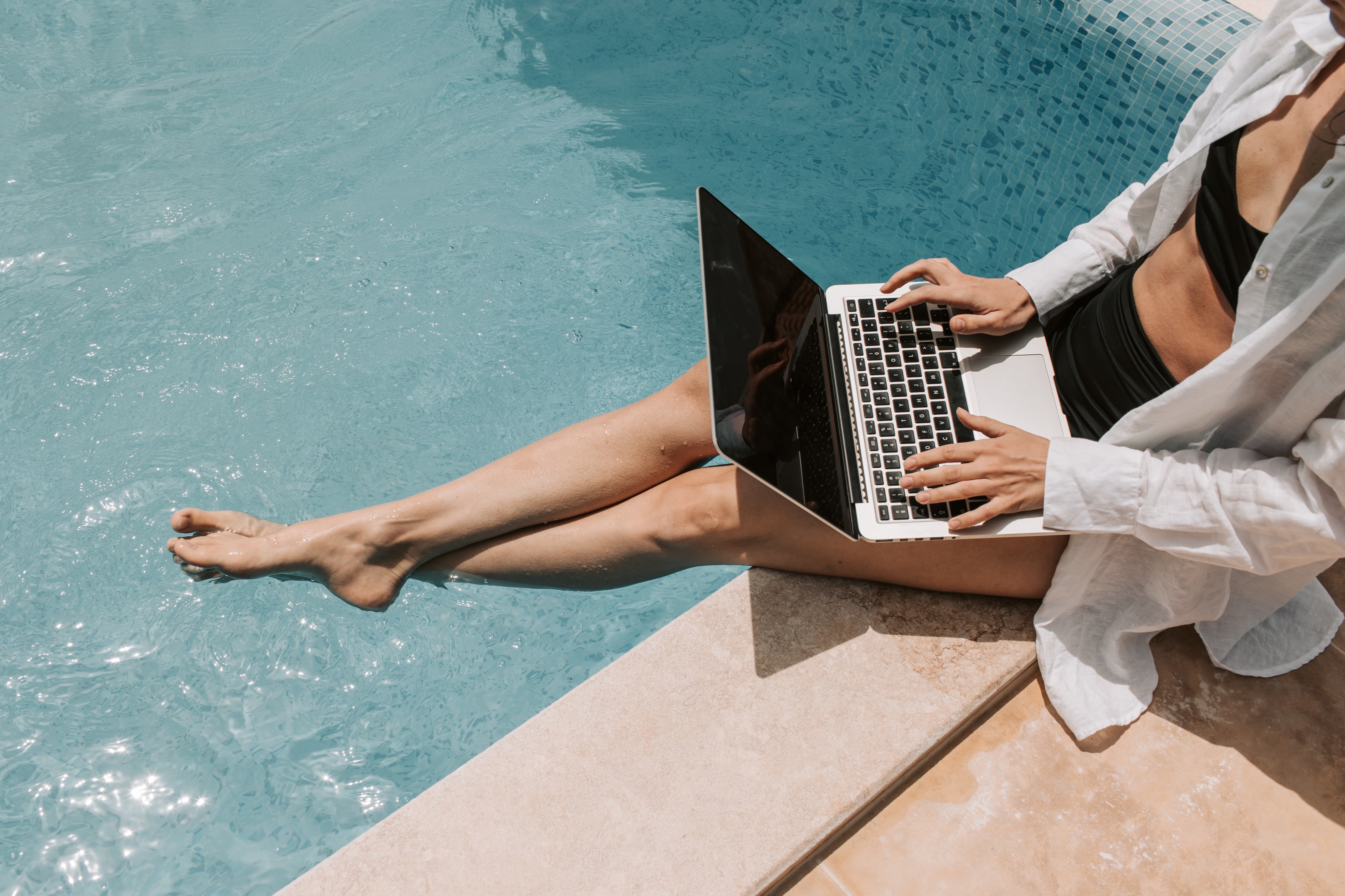 Person on laptop at pool stock image
