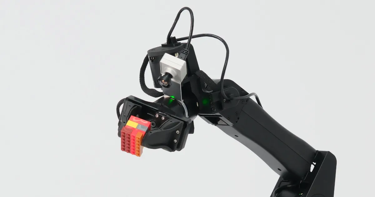 An industrial robot arm with a machine-vision head against a pale ground