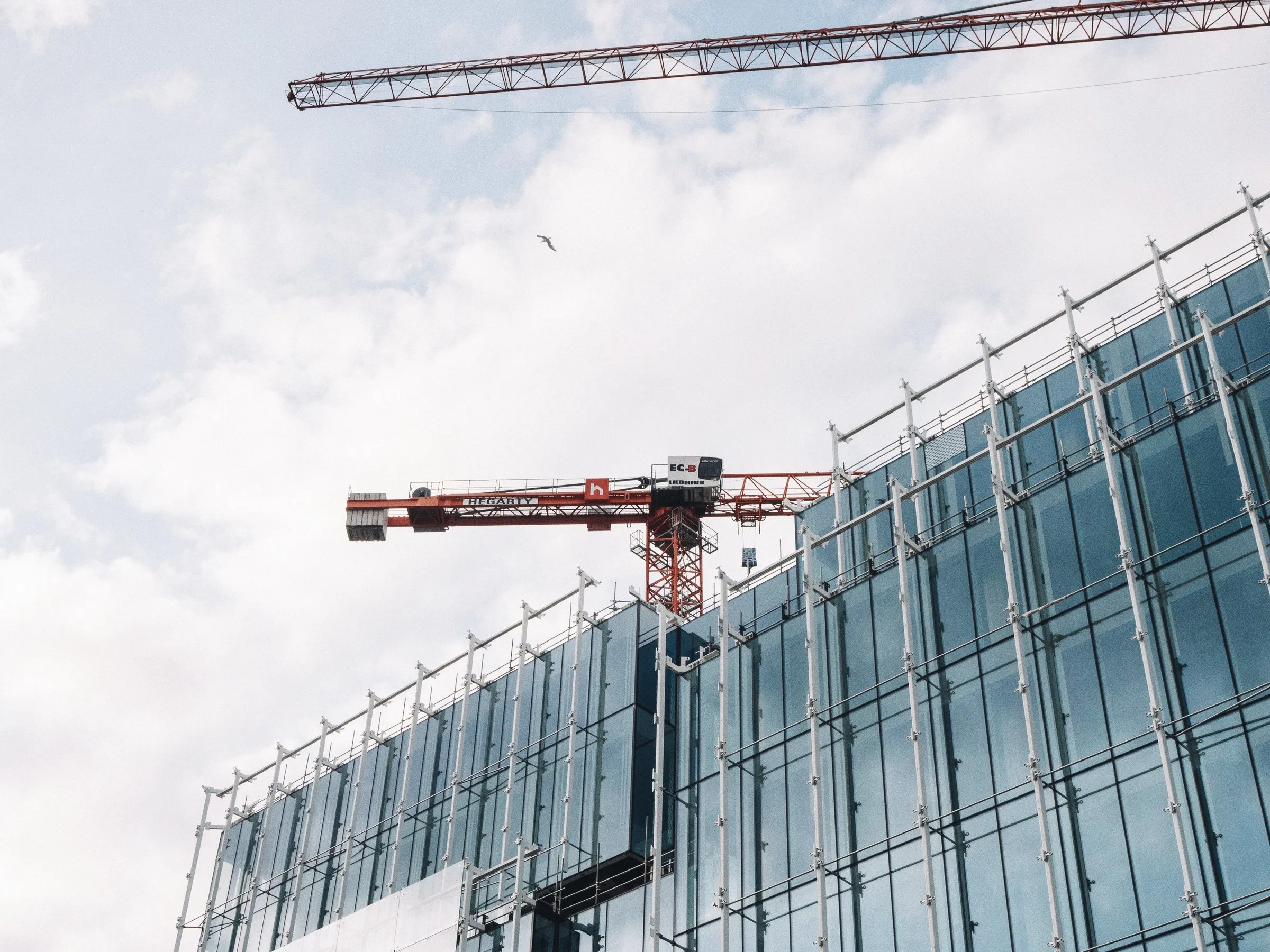 A tower crane working against the glass face of a building under construction