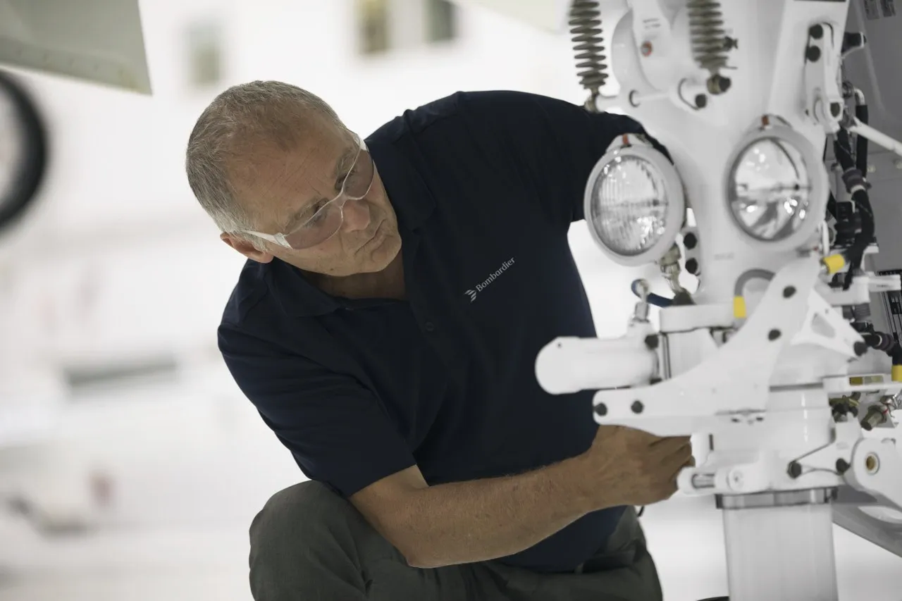 An engineer working on landing gear under an airframe