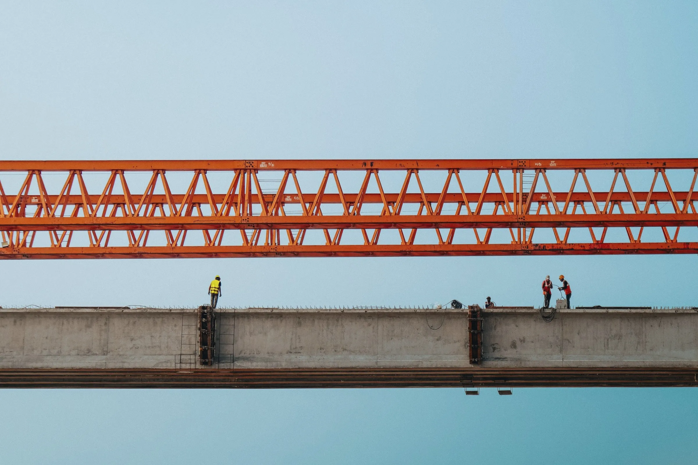 Workers standing on a bridge girder high against open sky