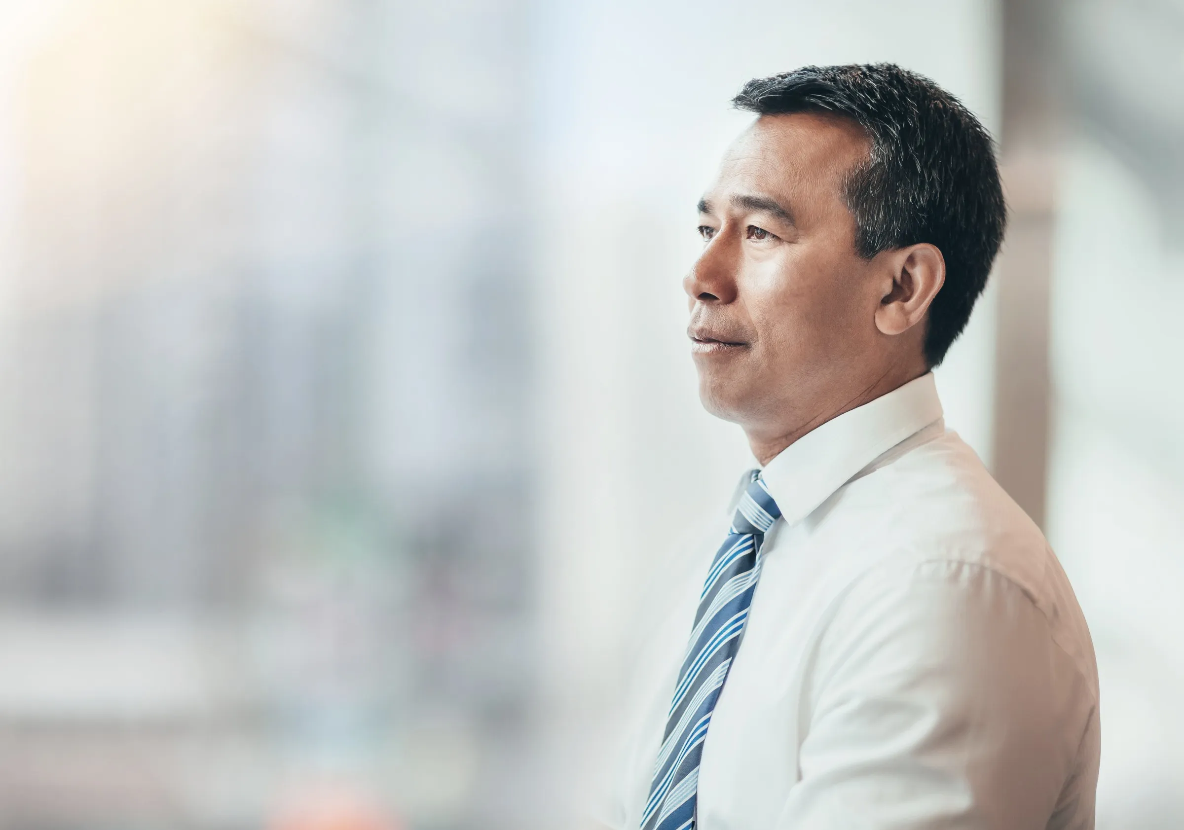An executive standing at a window, looking out