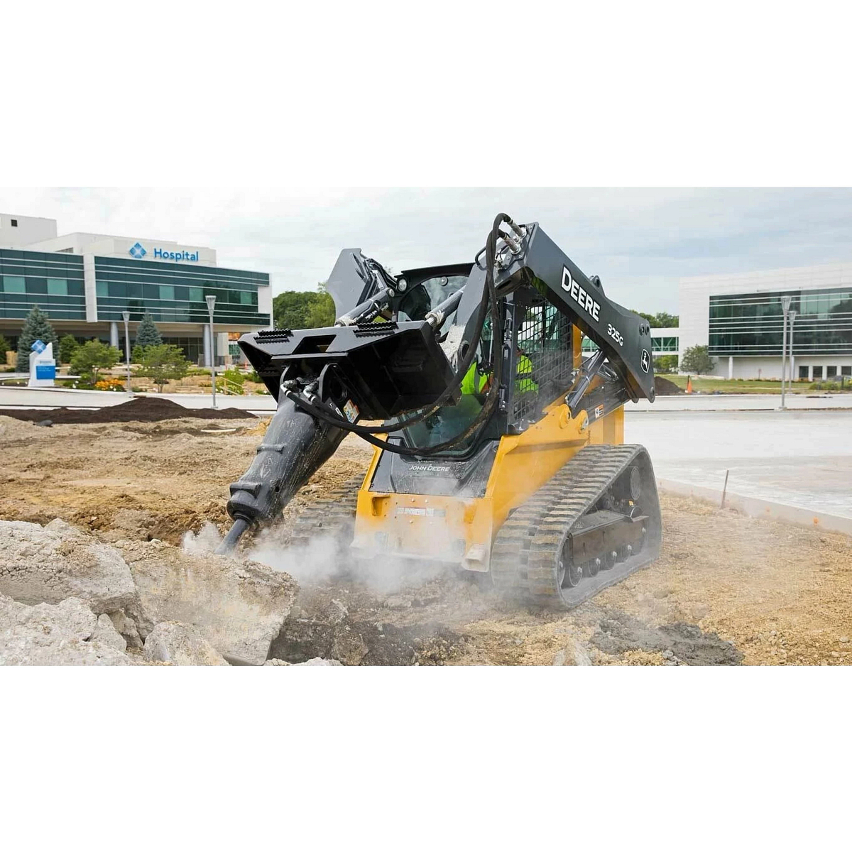 Front left view of 325G Compact Track Loader with hydraulic hammer breaking up concrete in a parking lot