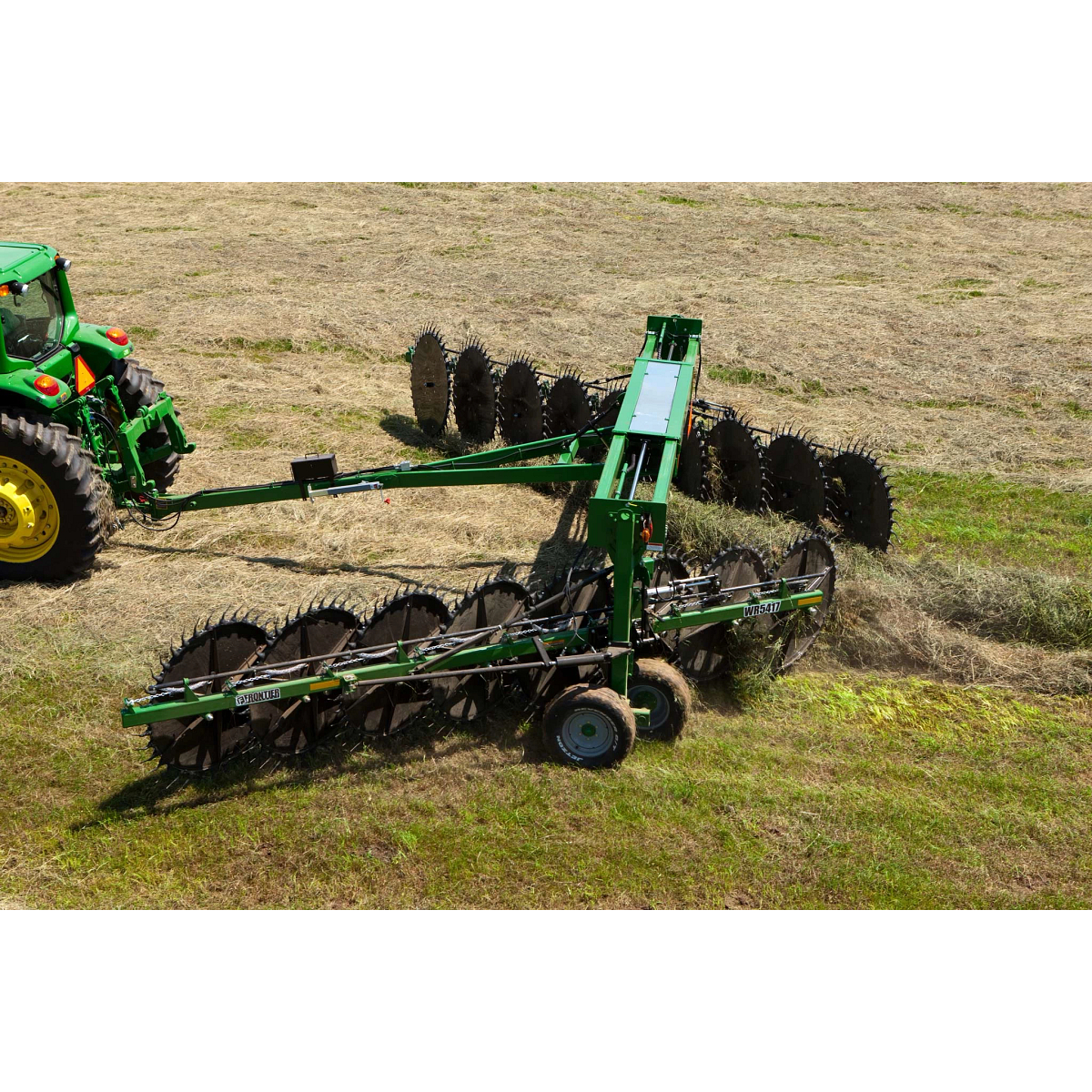 Aerial view of a WR high-capacity wheel rake being pulled across a hay field by a tractor