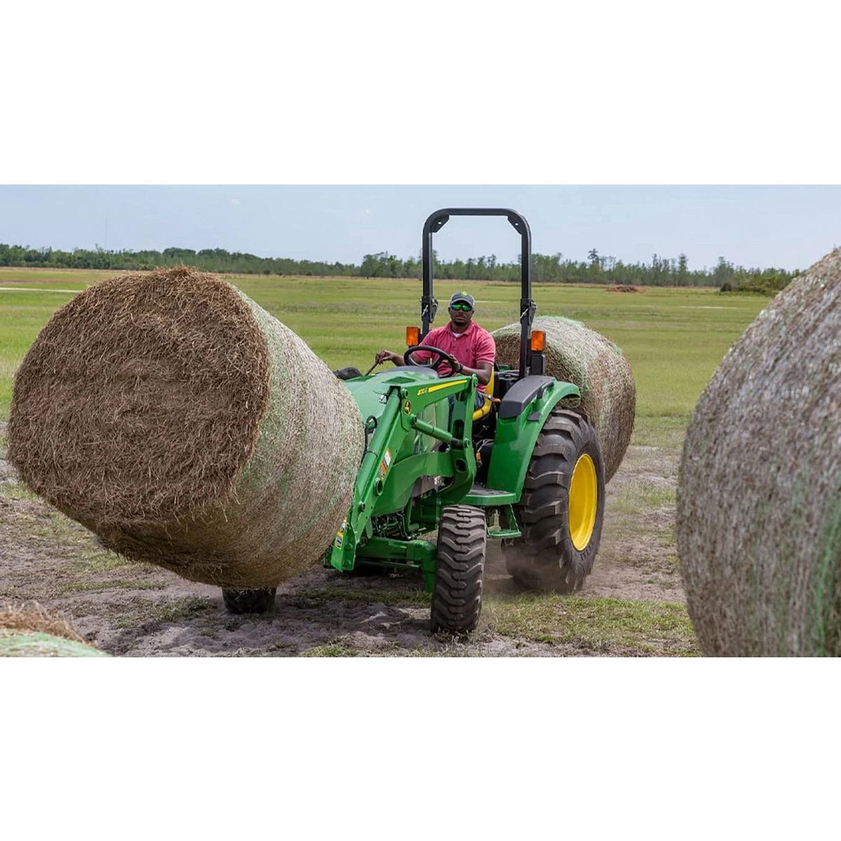 farmer operating a 4044M Compact Tractor to move hay bales