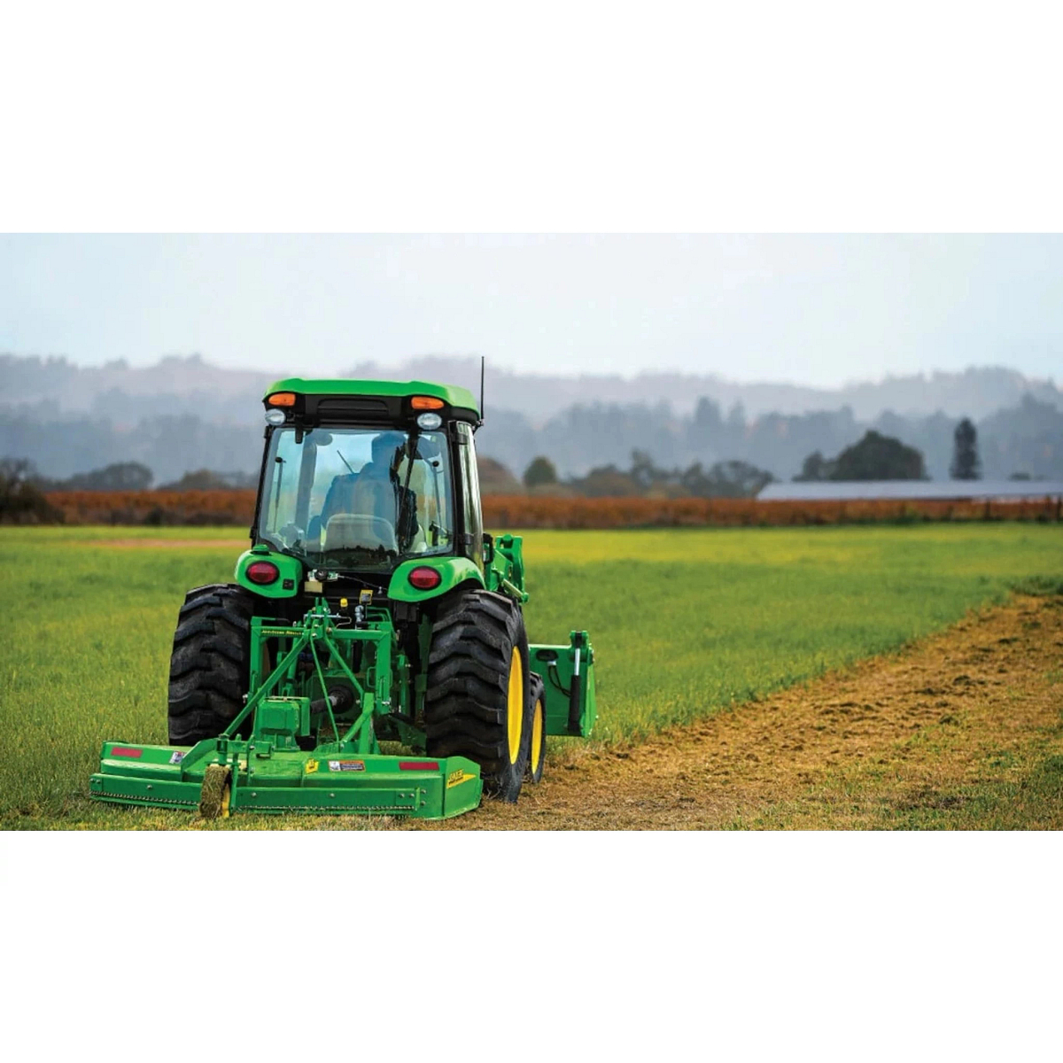 Farmer mowing a field with a 4052R Compact Tractor attachment