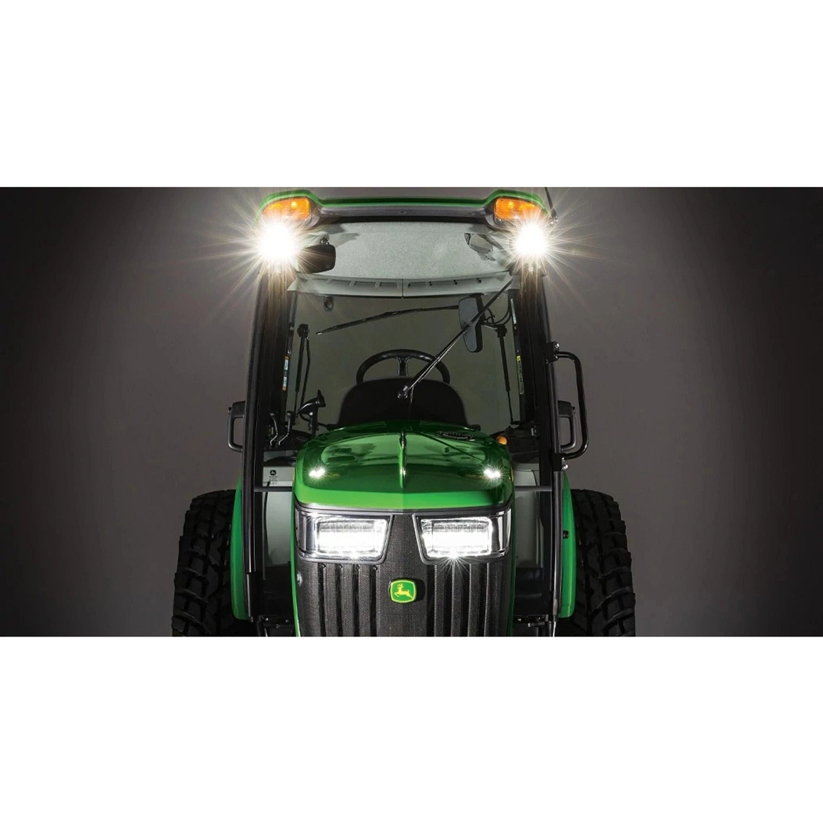 Front view of tractor in dark studio, highlighting the bright LED lights on top of cab and front of engine.