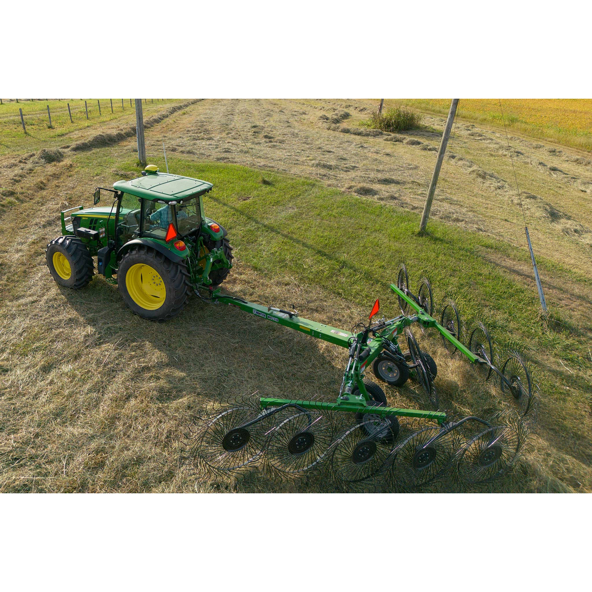 Top view of a 5M tractor pulling a WR3210 wheel rake across cut hay field