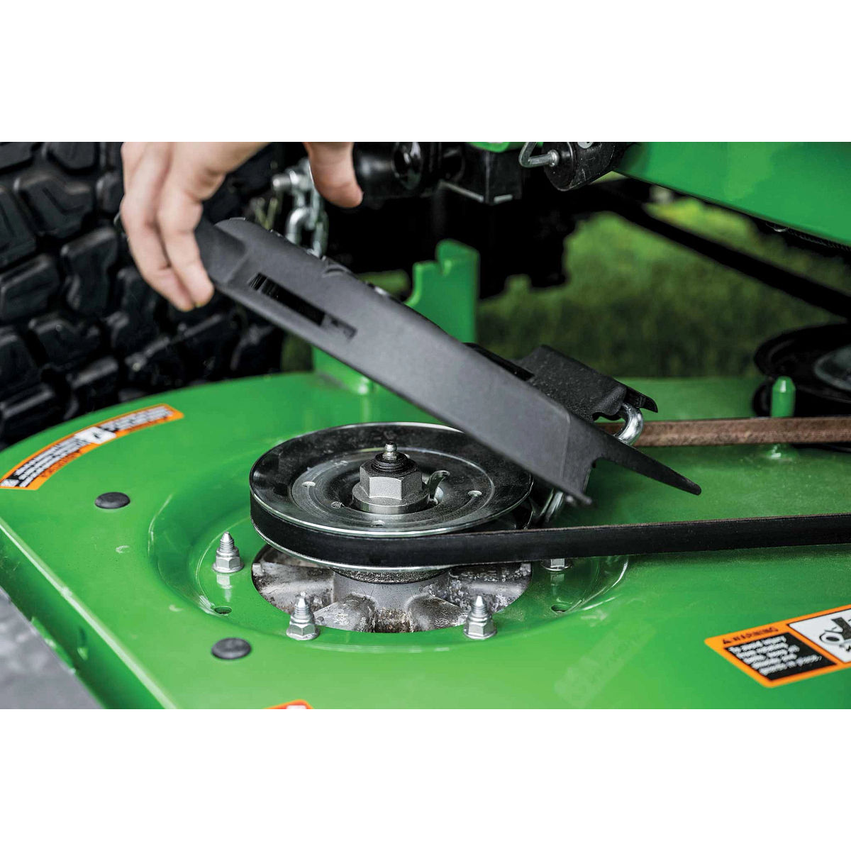 A close-up shot of the belt system on a green zero-turn mower deck.