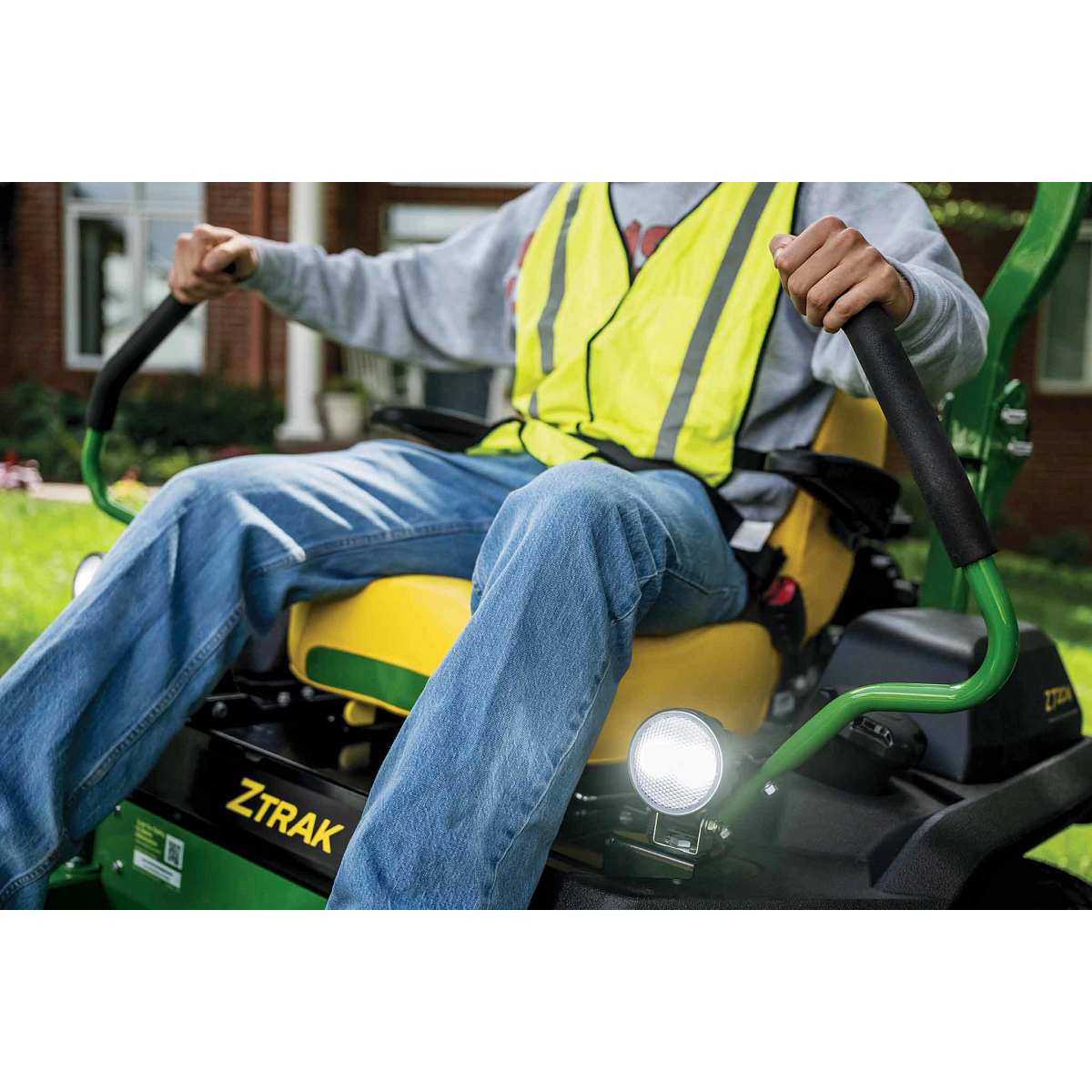 A zoomed-in shot of a landscaper operating a green Z720M zero-turn mower.