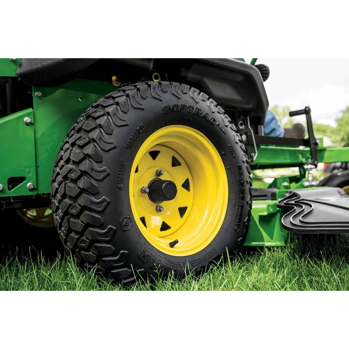 A close-up of a zero-turn mower tire with a yellow rim.