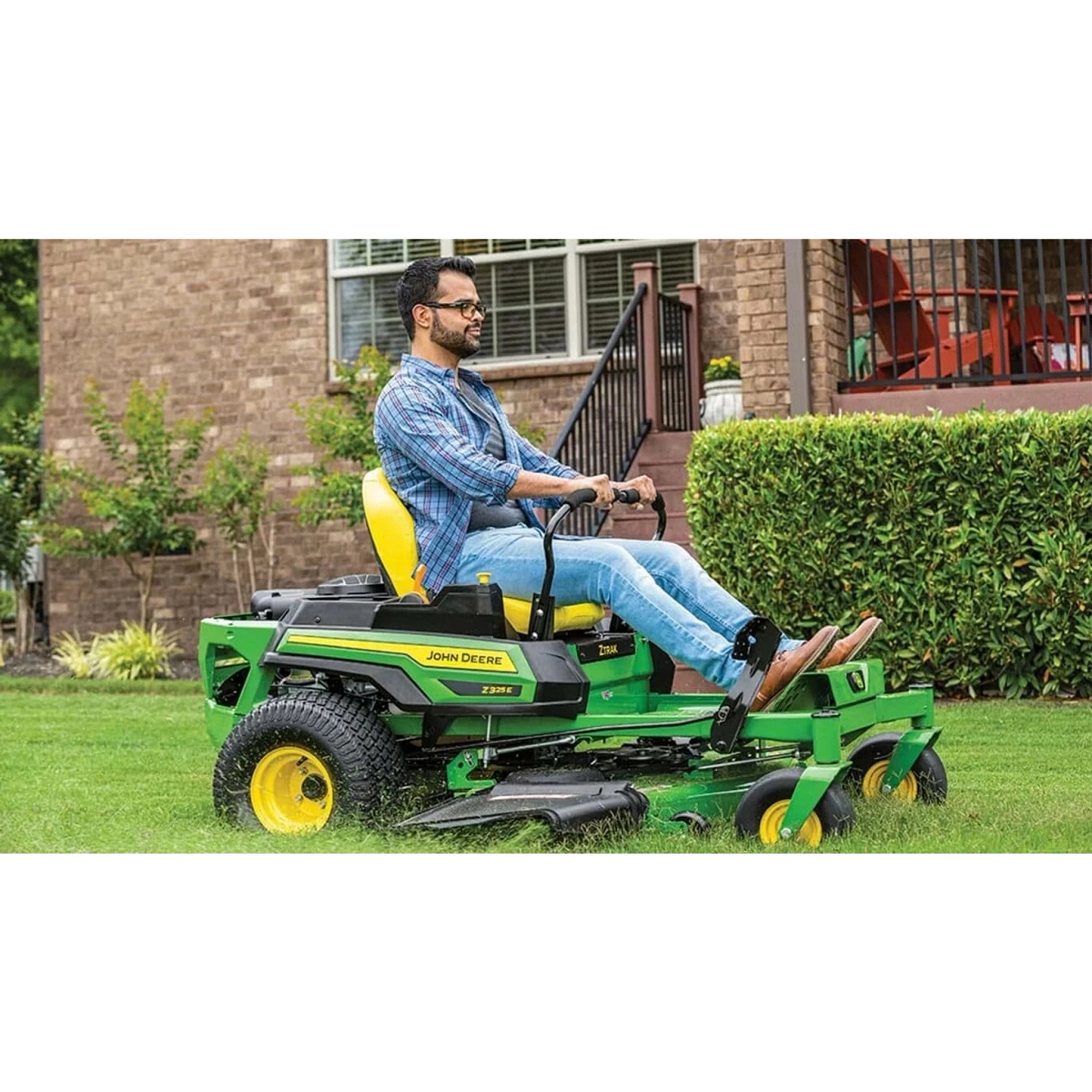 Homeowner mowing grass with a Z325E ZTrak Mower in front of a house