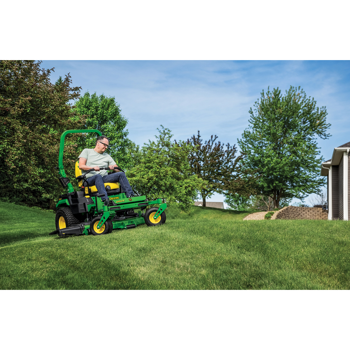 A Z550R zero-turn mower is used to mow the gentle sloped lawn of a residence.