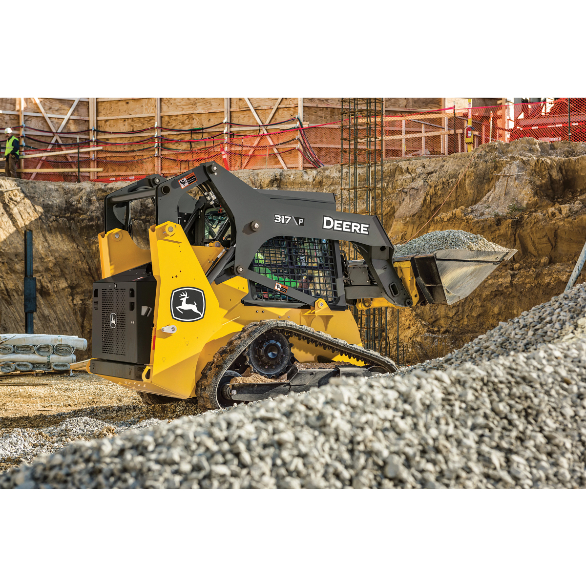 A 317 P-Tier Compact track Loader moving rocks on a construction site