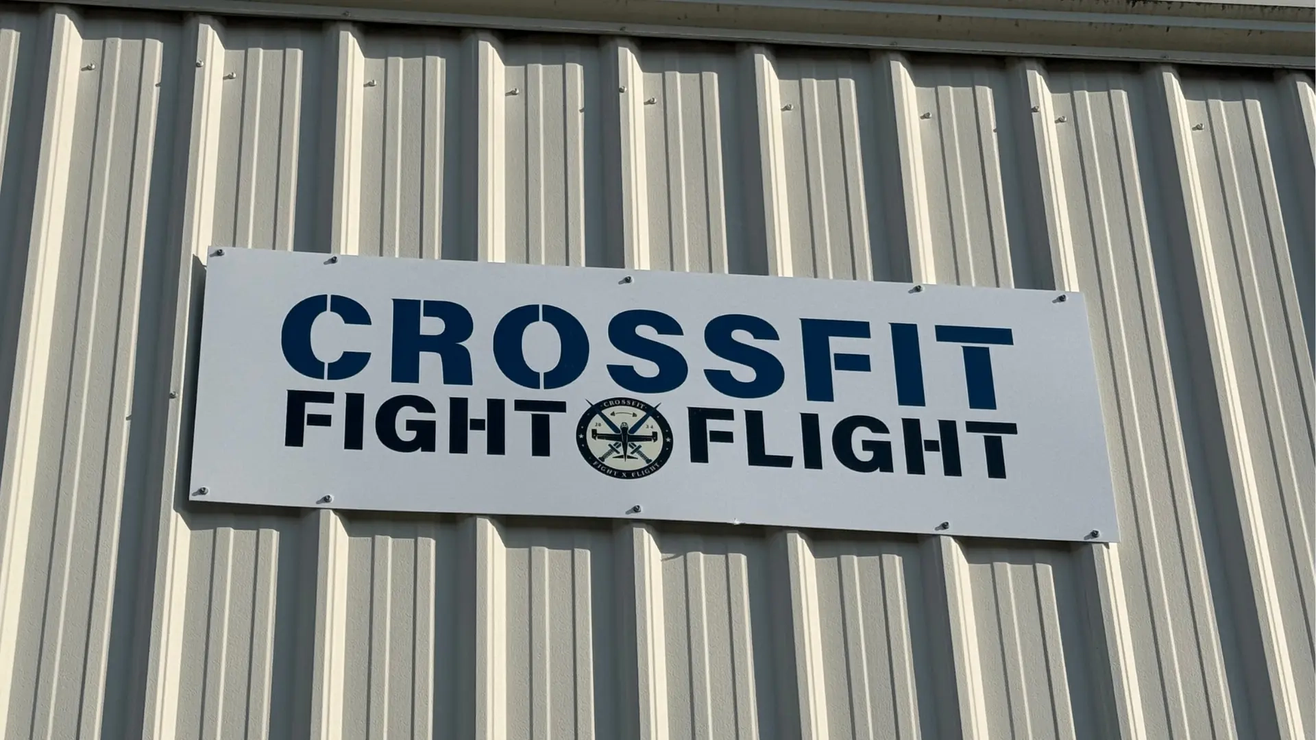 Exterior sign displaying the CrossFit Fight x Flight logo on the gym building.
