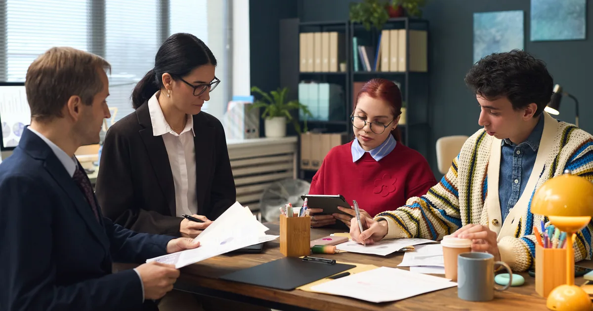 Colleagues reviewing documents and a tablet together at a meeting table