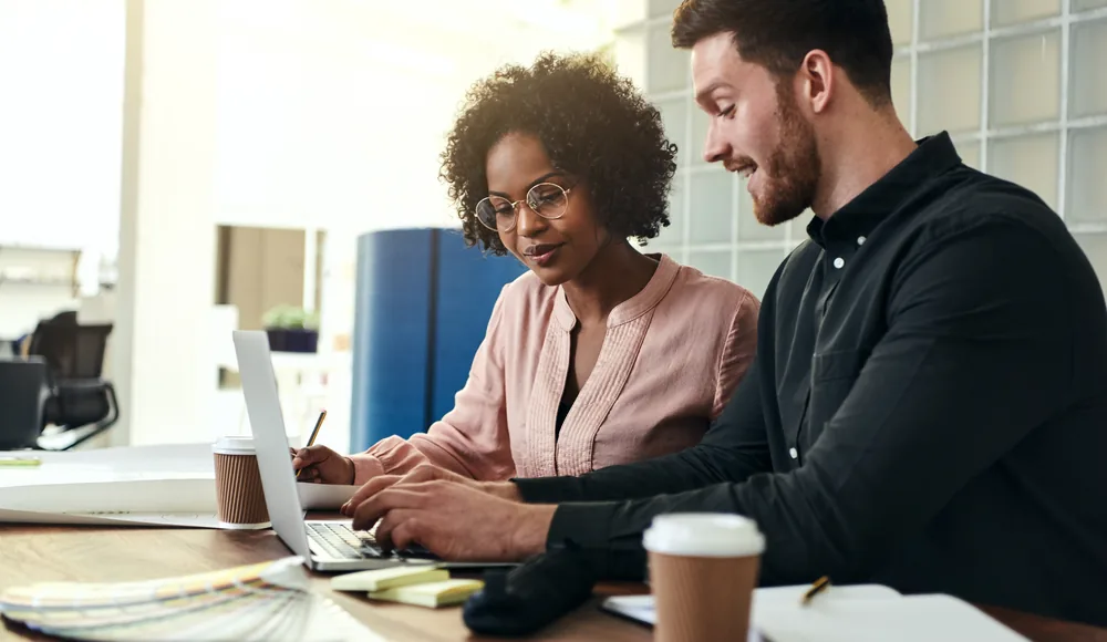 An advisor pointing at a laptop screen while a client follows along