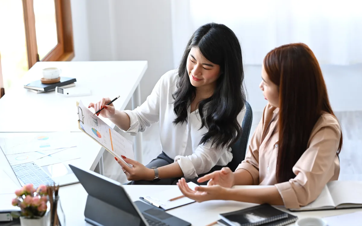 Two colleagues reviewing a document and charts together at a desk