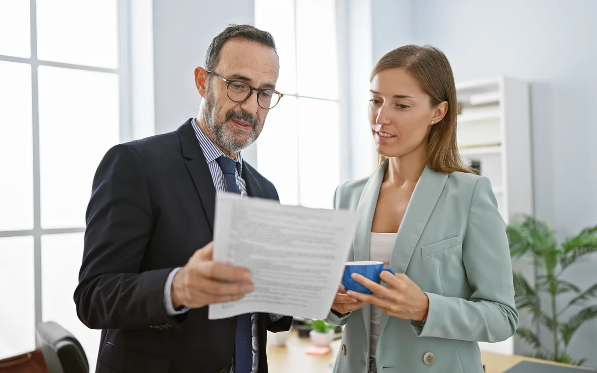 Two colleagues standing together reading the same document