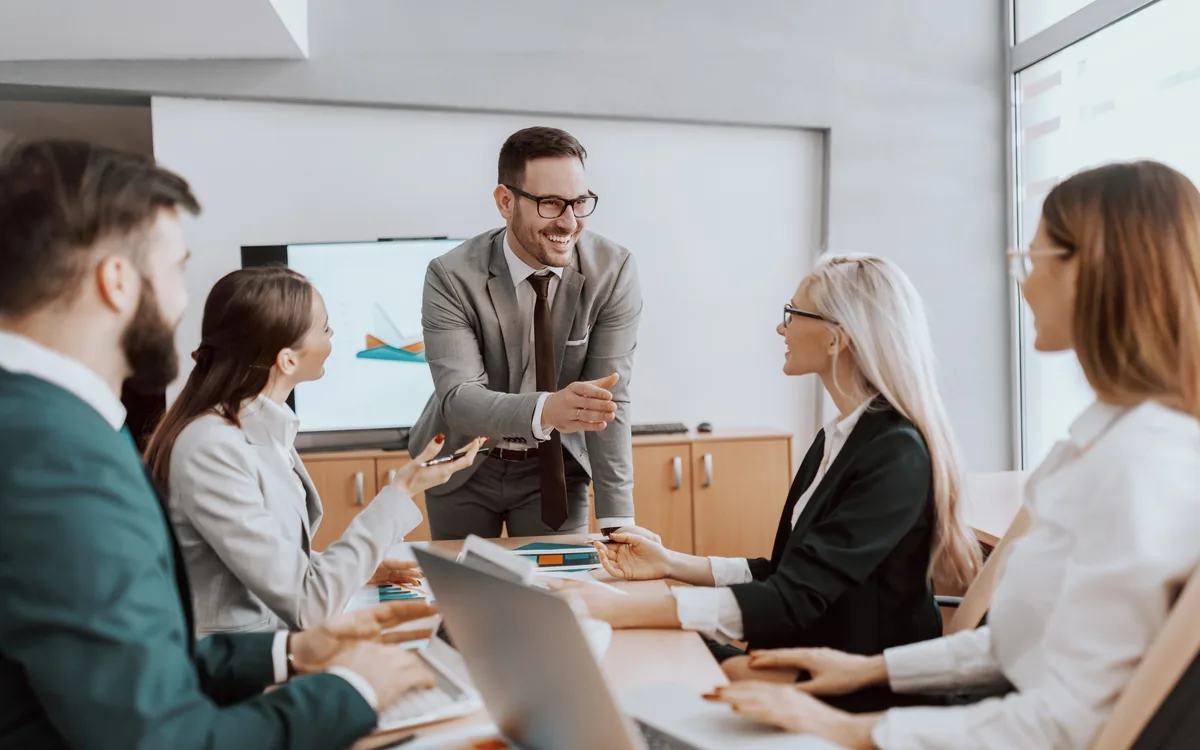 A colleague briefing seated leadership around a boardroom table