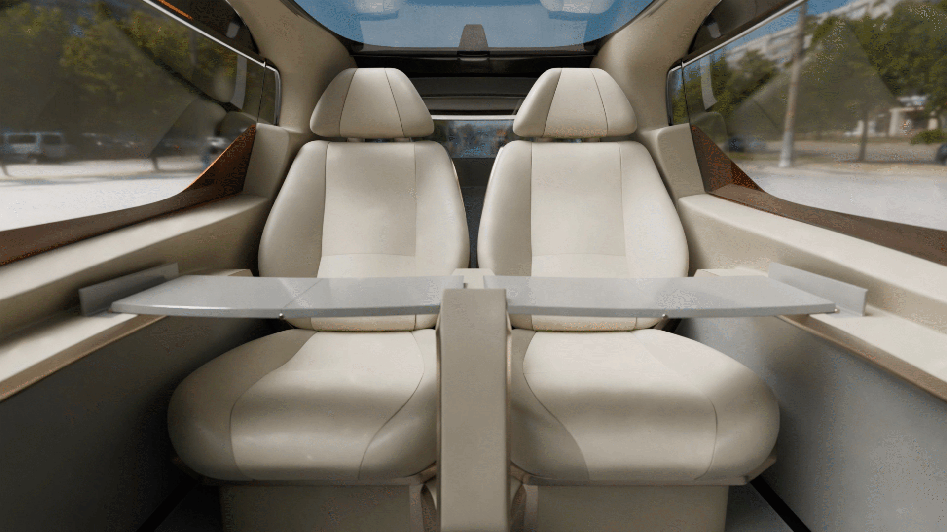 Interior view of two cream-colored car seats with a foldable table between them and large side windows.
