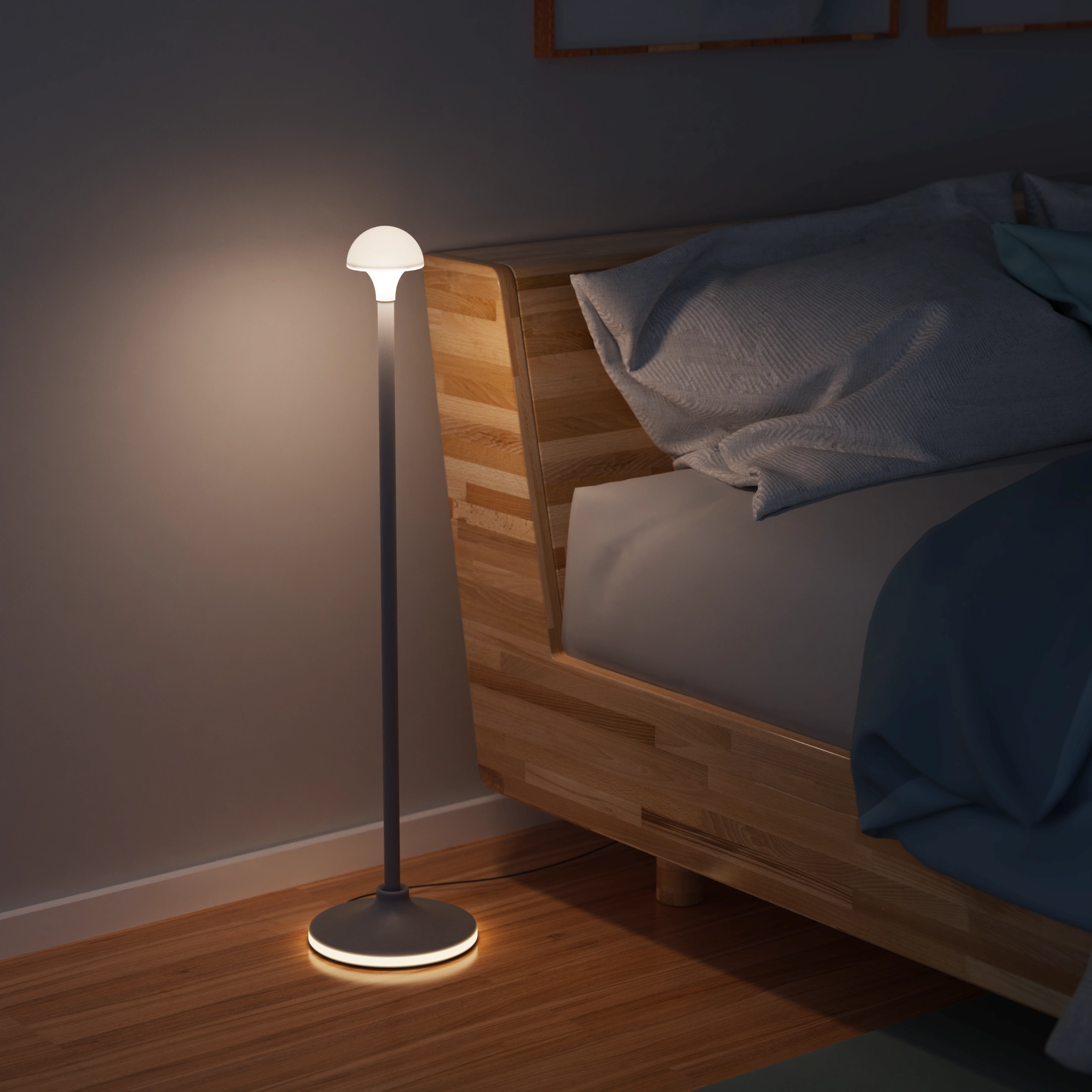 Modern floor lamp with round base and dome-shaped light beside a wooden bed with pillows at night.