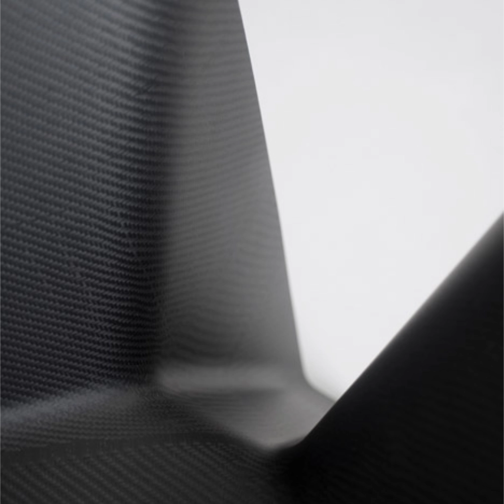 Close-up of black carbon fiber material with a textured weave pattern.