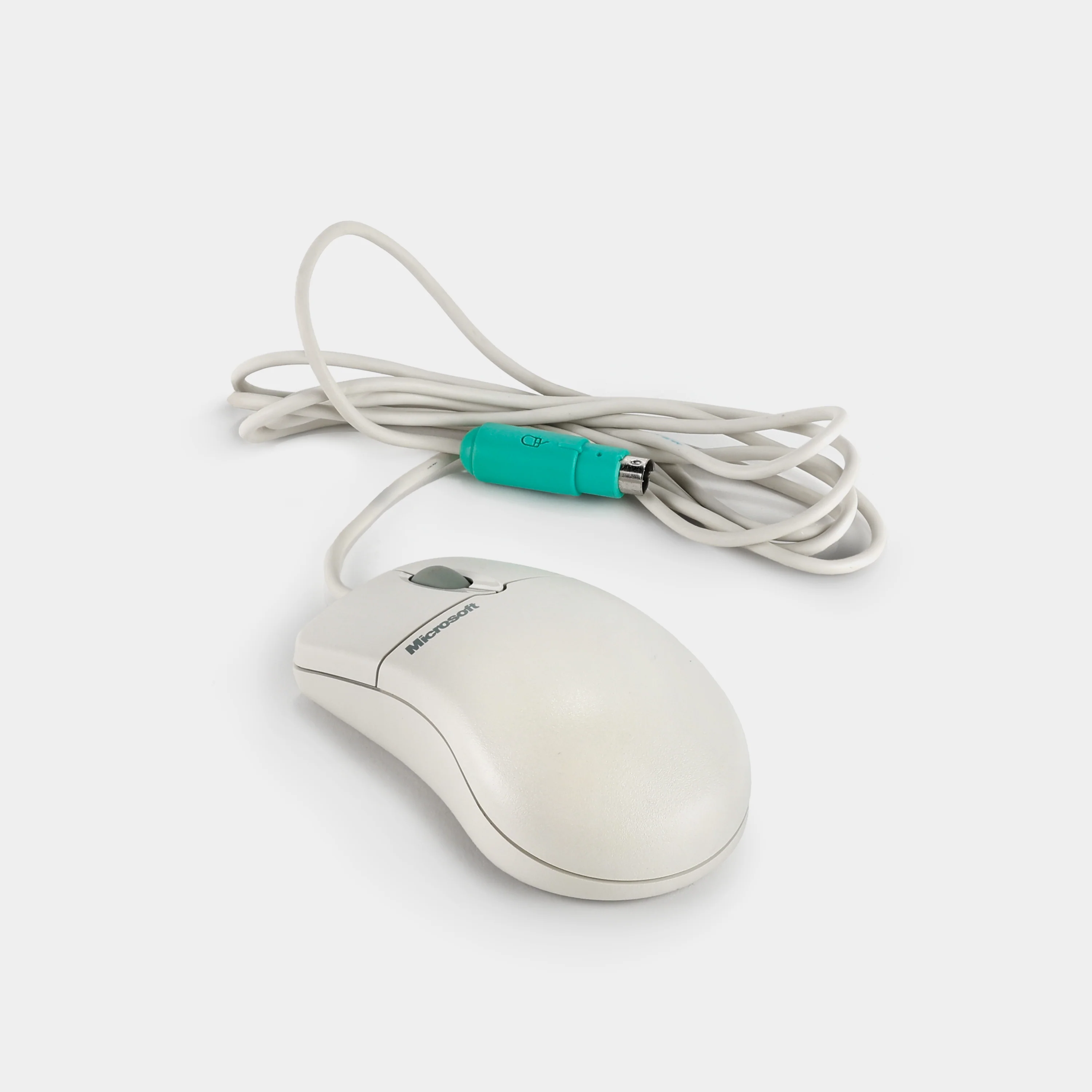 White wired Microsoft computer mouse with gray scroll wheel and green PS/2 connector plug.