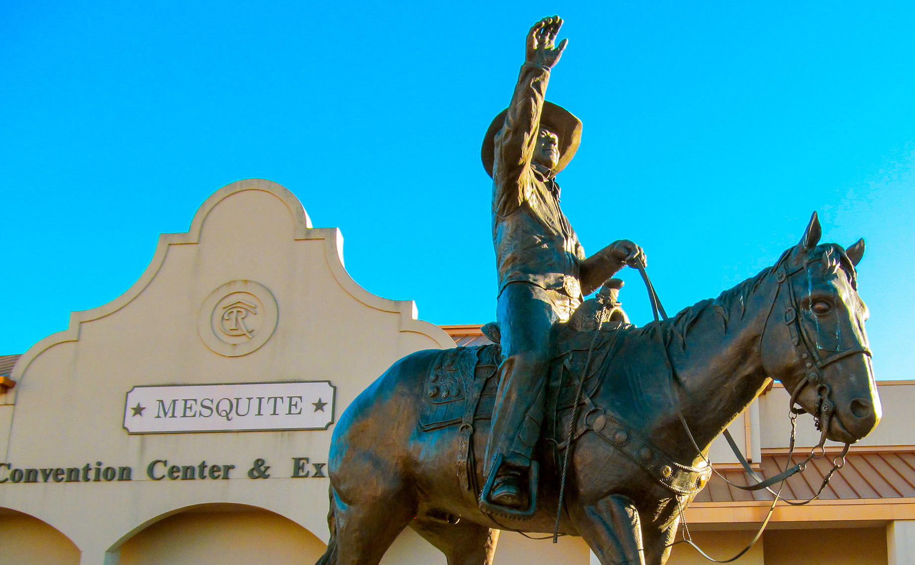 A bronze statue of a rider on a horse outside the Mesquite Convention Center.