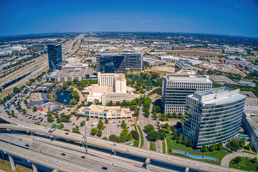 An aerial view of Plano office towers and a busy highway on a clear day.