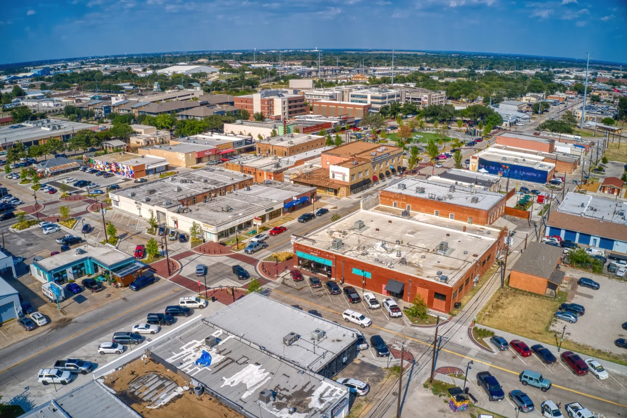 Aerial view of downtown Garland with brick storefronts, streets, and parking lots.