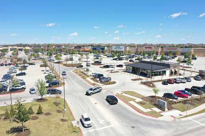A shopping center in Prosper with cars in the parking lot on a clear day.