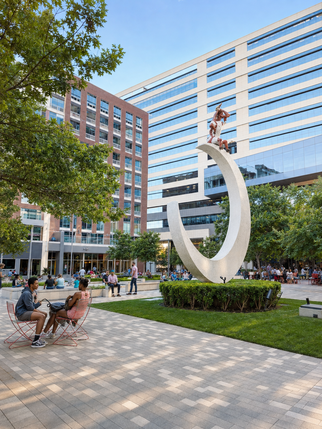 A plaza in Richardson with a tall white sculpture, office buildings, and people sitting outside.