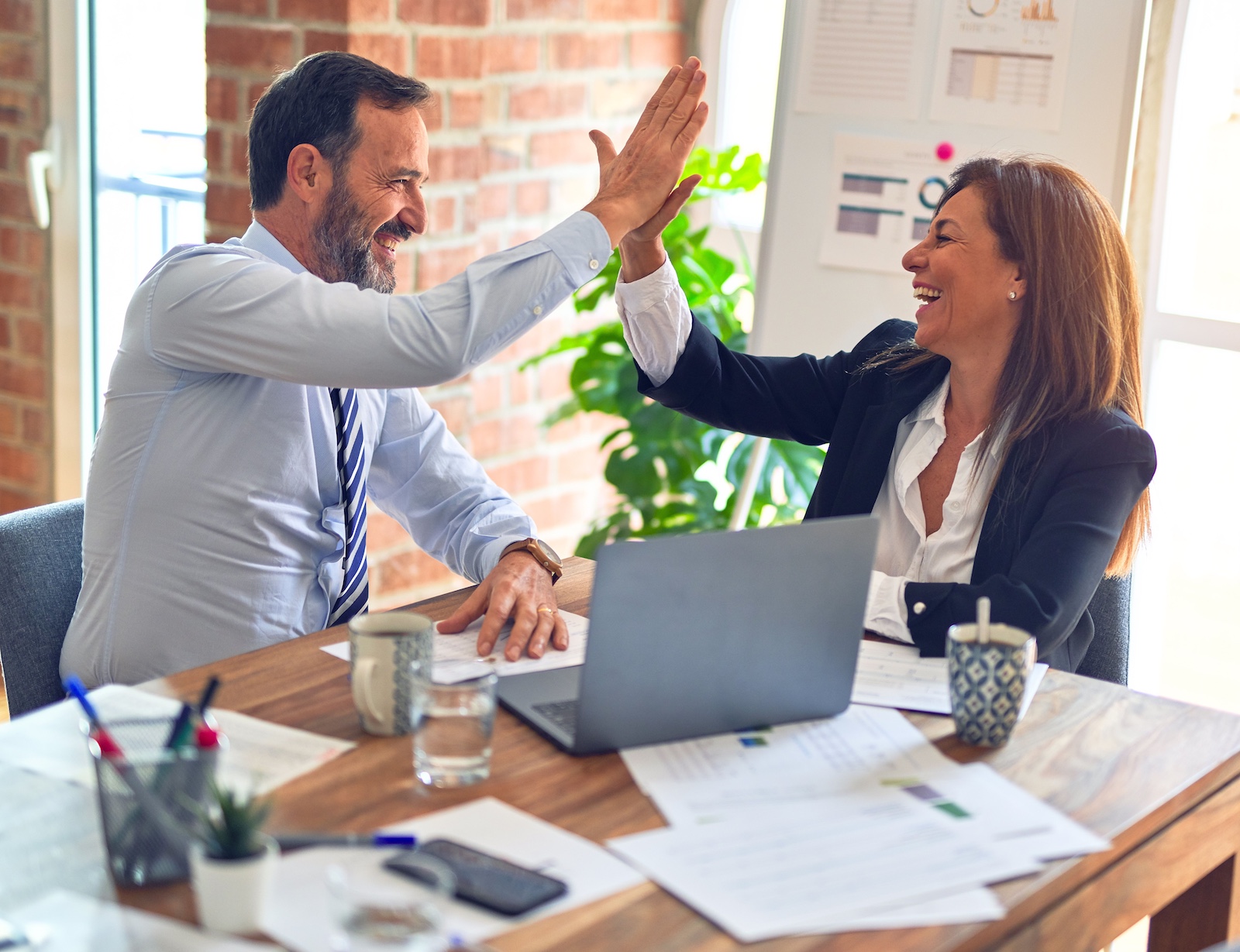 Man and woman in office setting giving each other high five