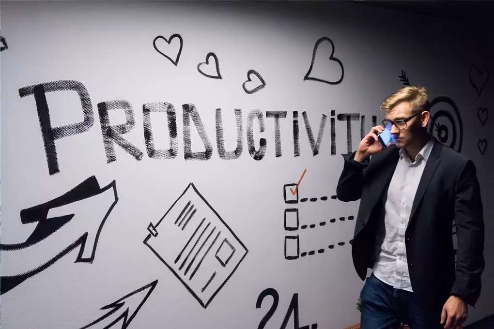 Businessman on a phone call in front of a wall sketched with the word Productivity