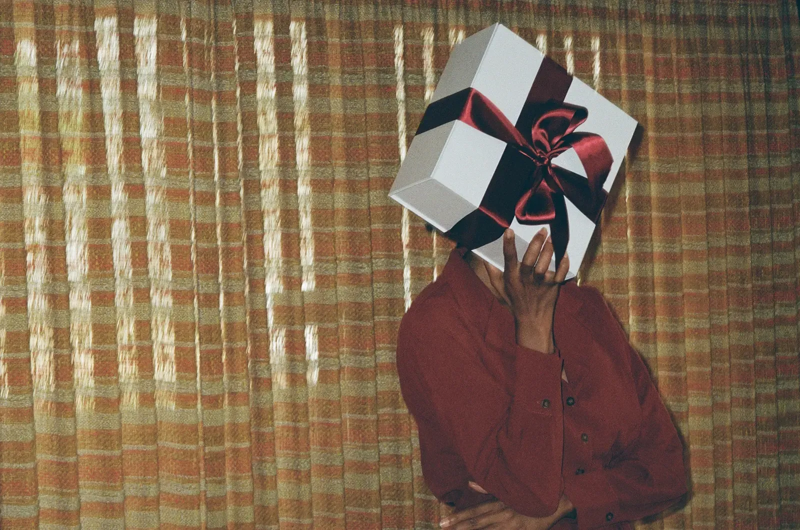 A client holding a gift box tied with a burgundy ribbon