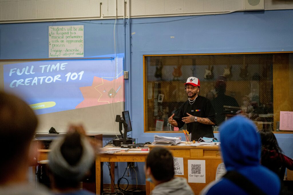 Teacher leading a lecture in class for K-12 schools with blue wall and slides profection on a screen