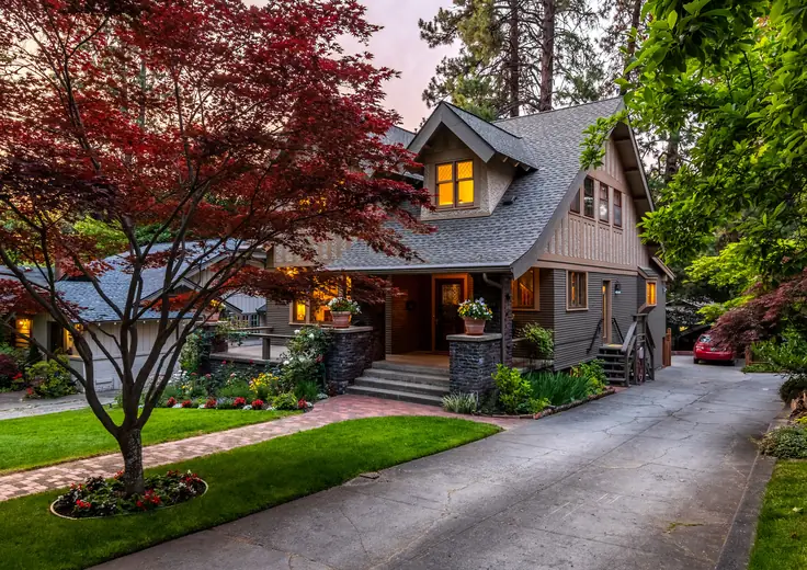 Craftsman-style rental house with landscaped front yard and driveway at dusk